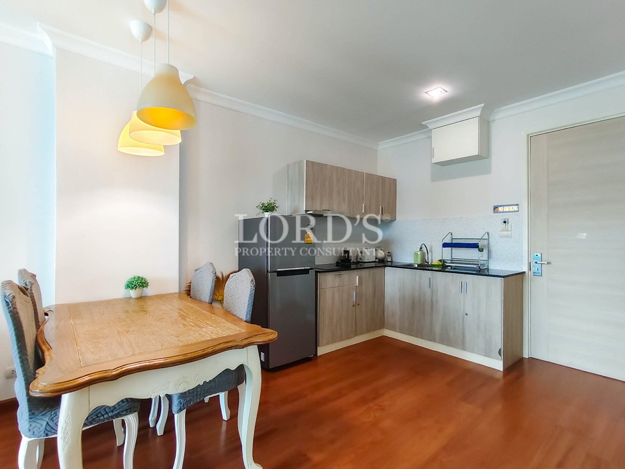 Modern apartment dining area with wooden table, upholstered chairs, and compact kitchen