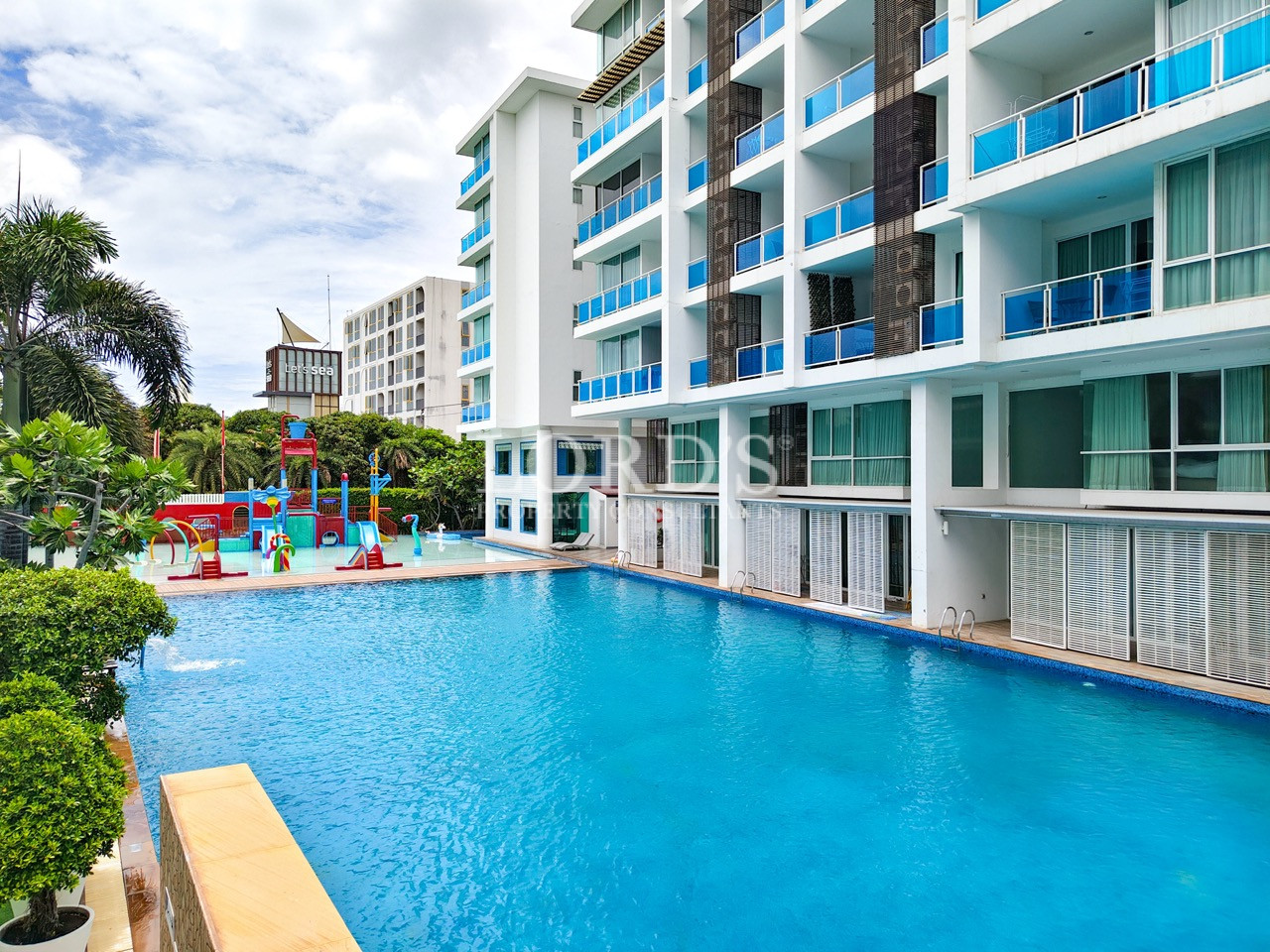 Modern resort apartment building with a large outdoor swimming pool and children’s water play area
