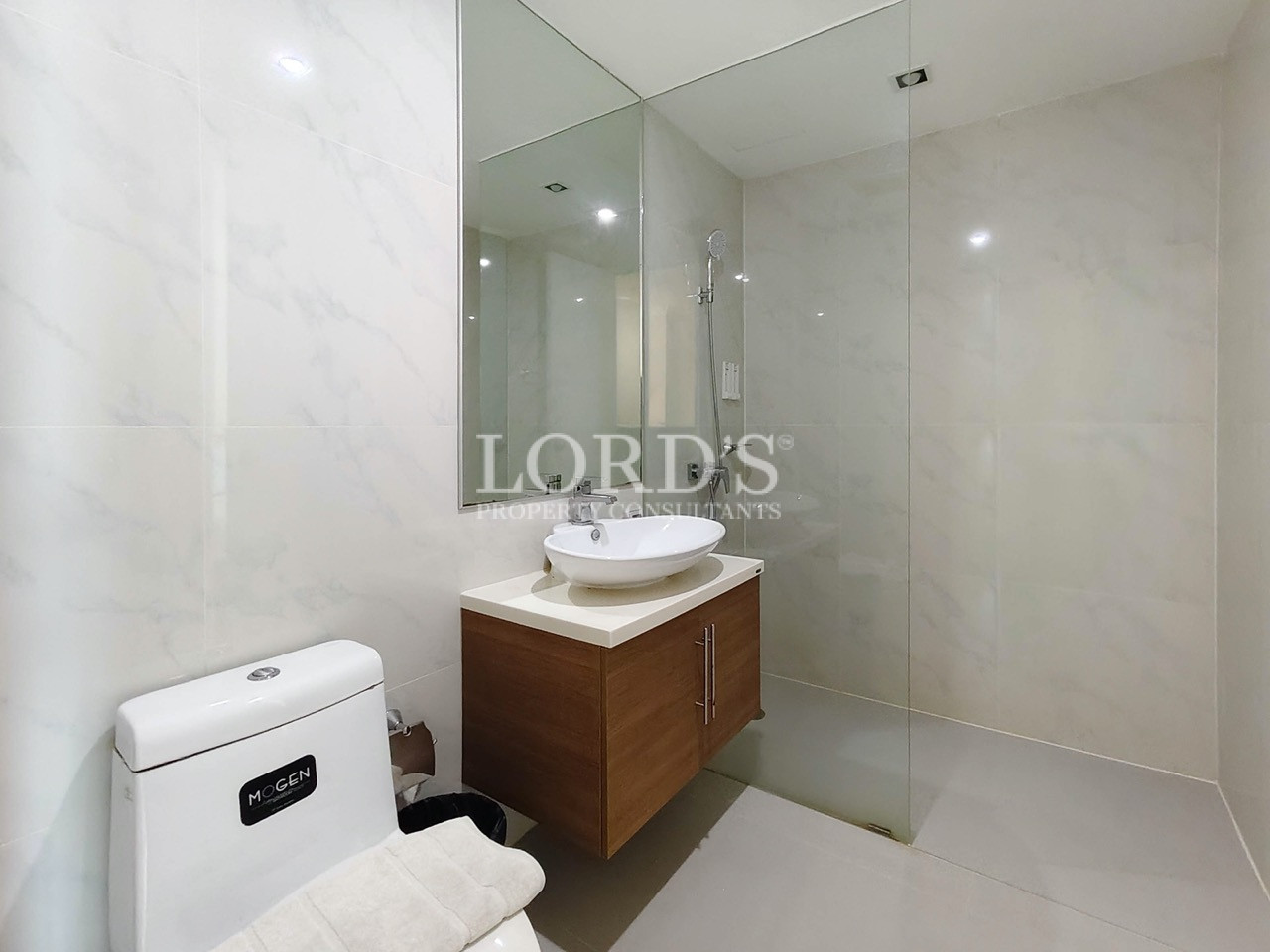 Modern bathroom with glass shower enclosure, floating wooden vanity, vessel sink, and white tiled walls