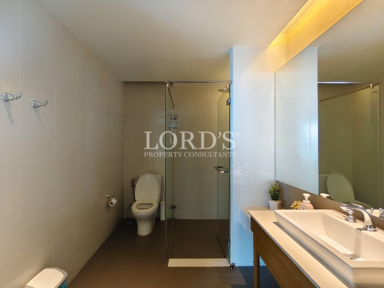 Modern bathroom with glass-enclosed shower, toilet, and wooden vanity