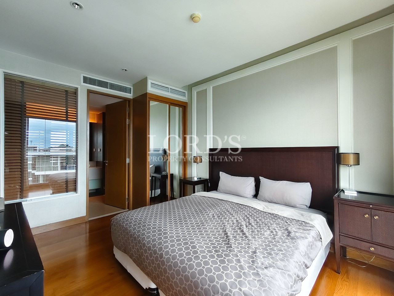 Modern bedroom with king-size bed, bedside tables, and mirrored wardrobe