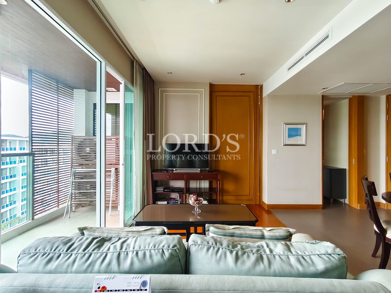Modern living room with sofa, coffee table, TV, and private balcony