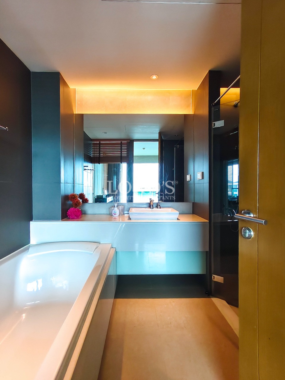 Modern bathroom with bathtub, vanity, and large illuminated mirror