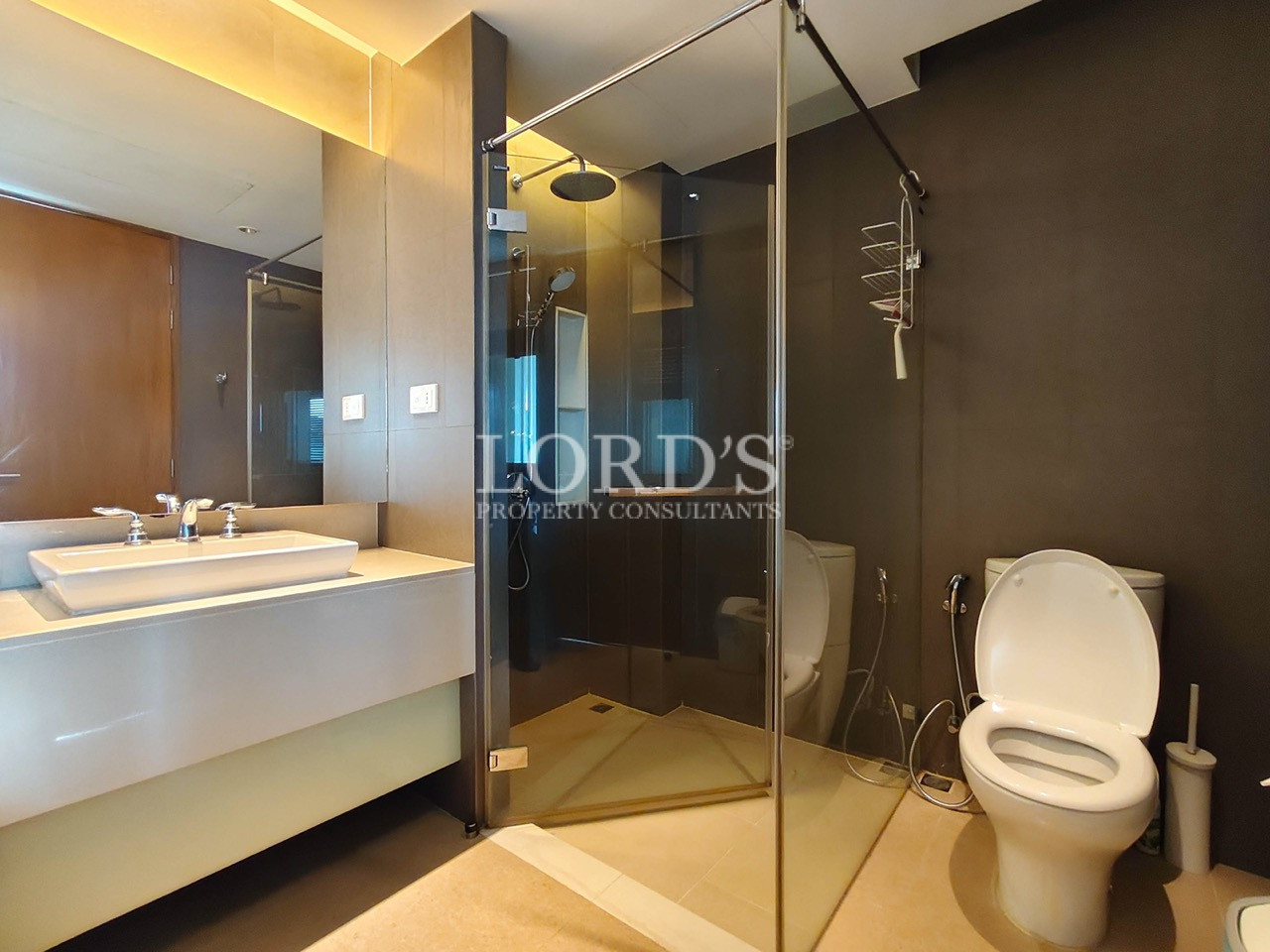 Modern bathroom with glass shower enclosure, vanity, and toilet