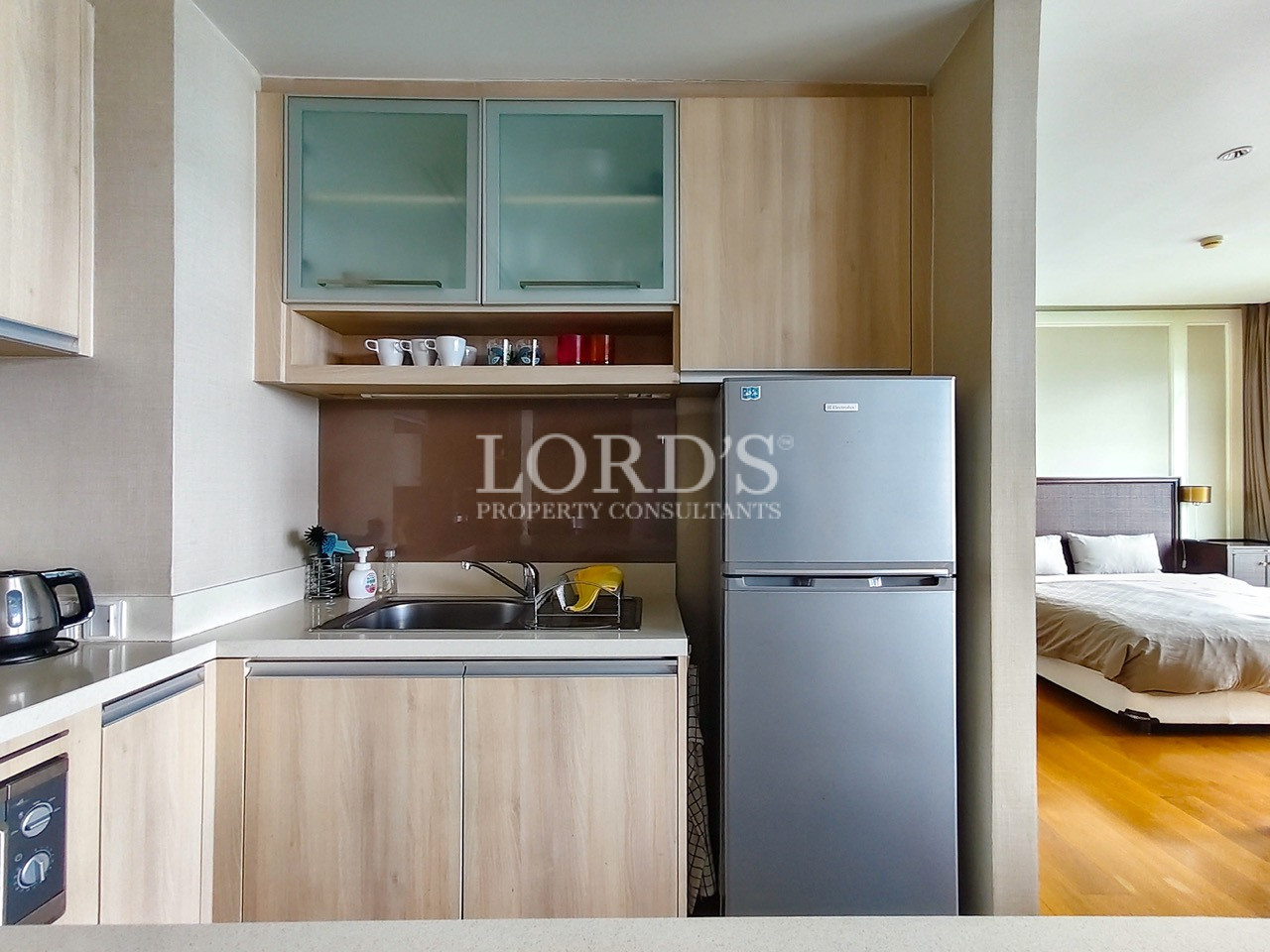 Modern compact kitchen with wooden cabinets and refrigerator