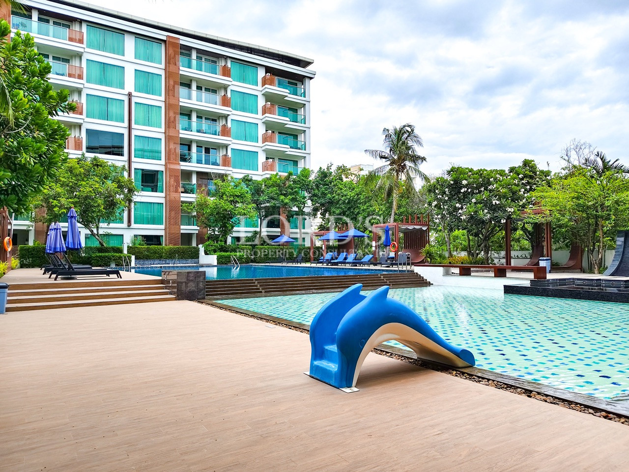 Luxury resort pool with dolphin slide and tropical landscaping