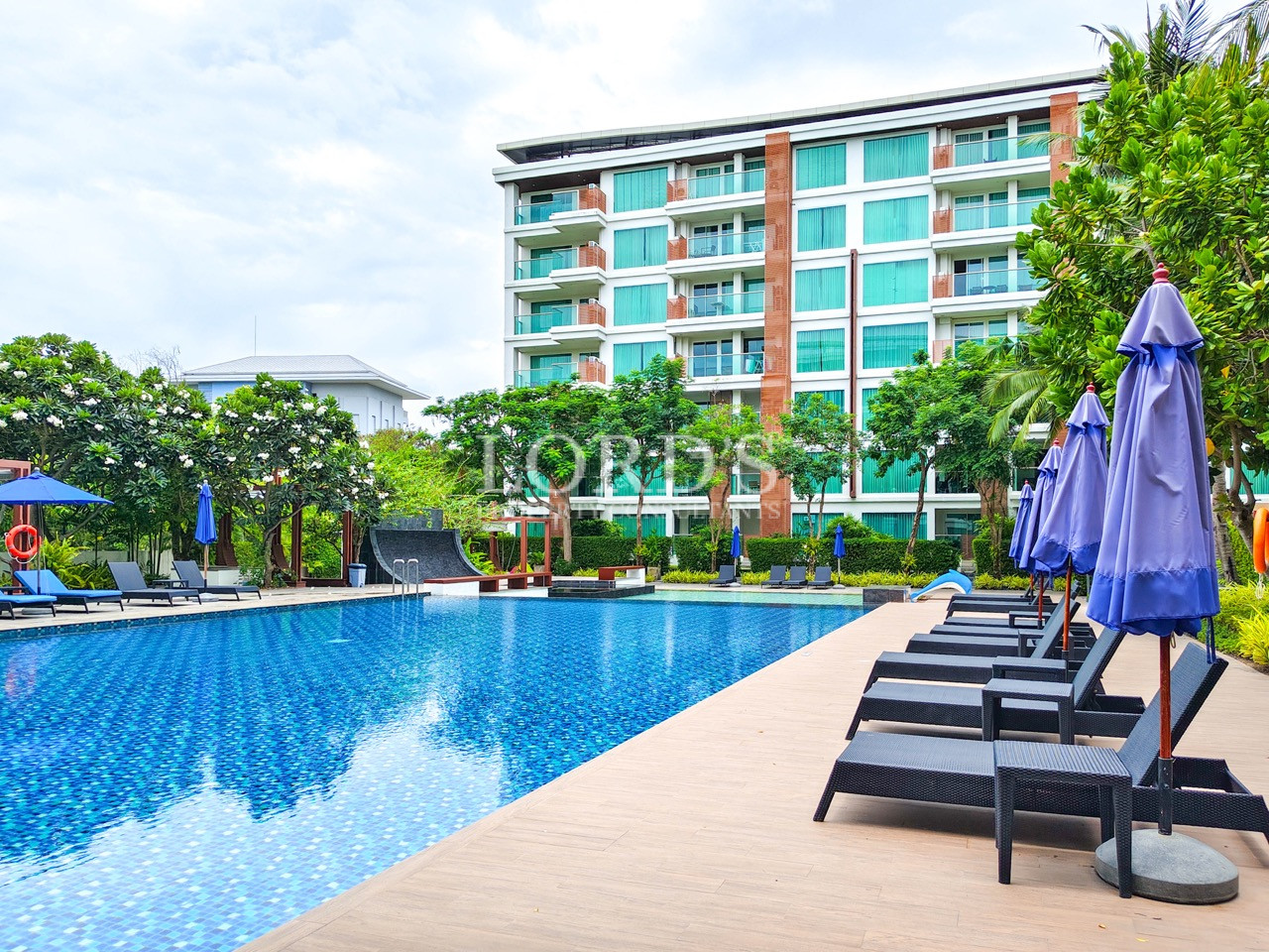 Luxury resort pool with sun loungers and modern hotel building