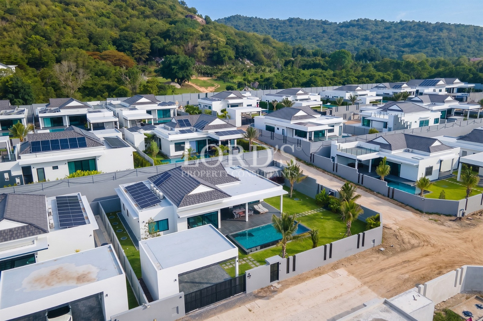 Aerial view of a modern luxury villa community with private pools and lush green hills