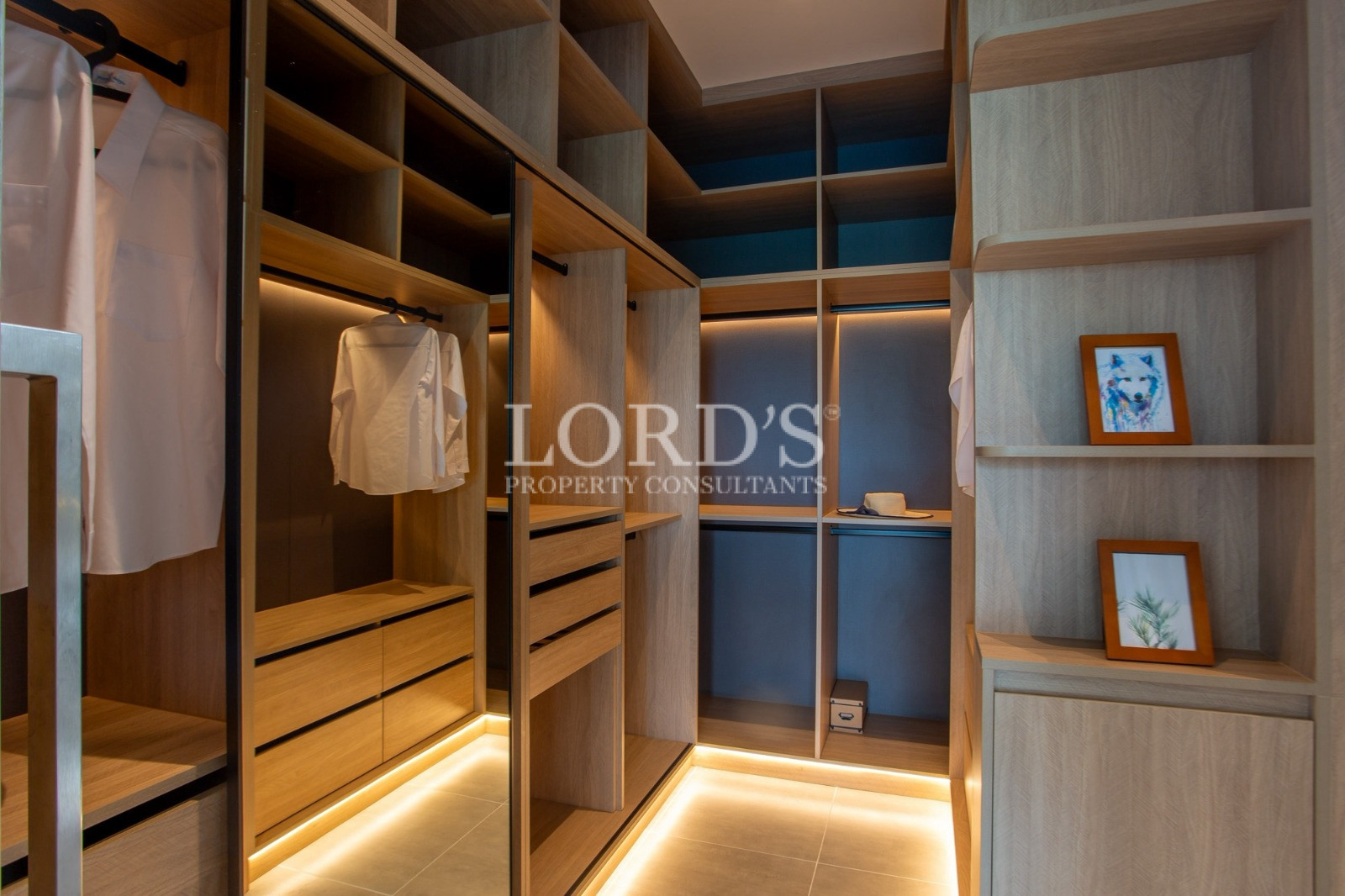 Modern walk-in wardrobe with custom wooden storage and LED lighting