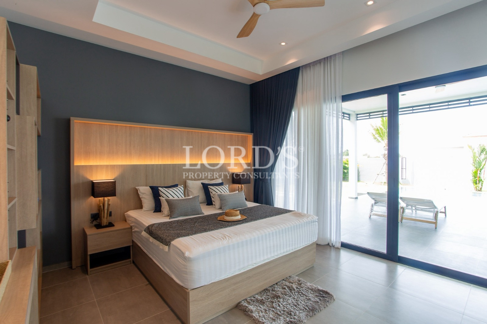 Modern luxury bedroom with illuminated wood headboard and pool view