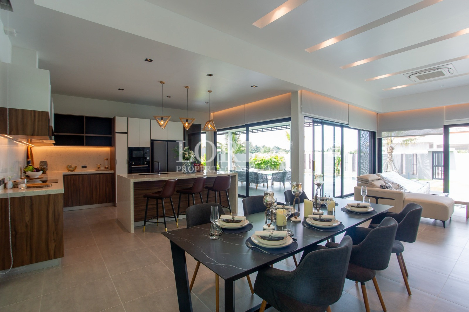 Modern open-plan kitchen and dining area with pool view