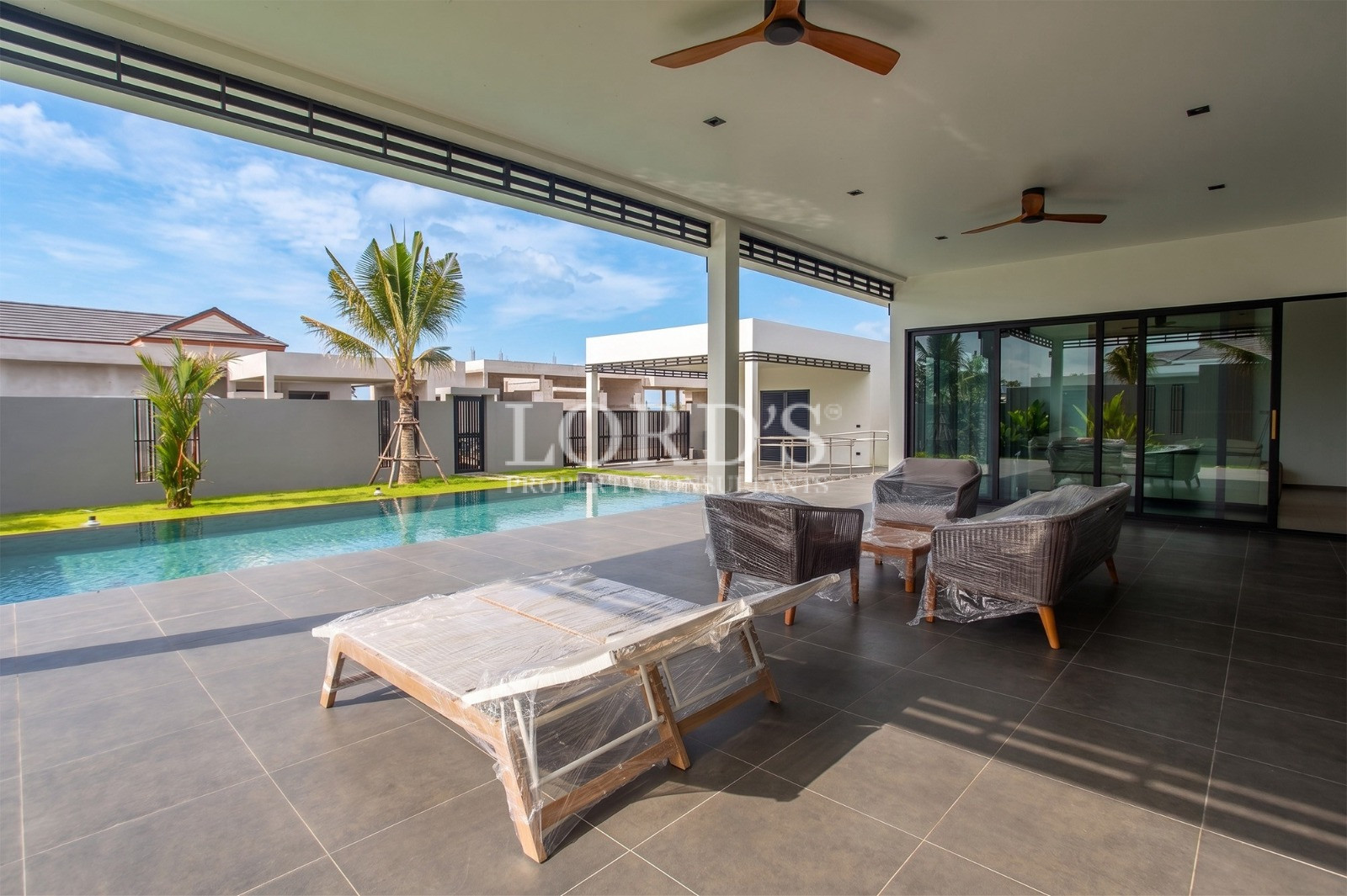 Modern villa poolside terrace with outdoor seating, palm trees, and private swimming pool