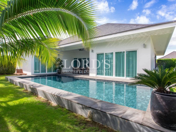 Private swimming pool surrounded by tropical greenery and a modern villa