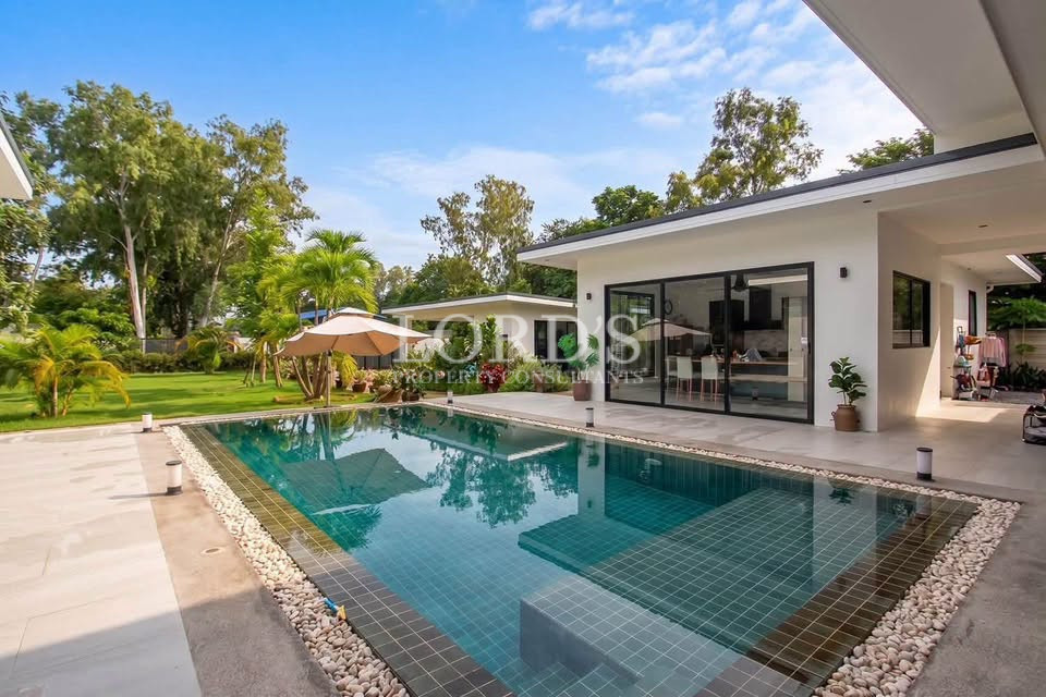 Private swimming pool beside a modern villa with landscaped garden and outdoor seating.