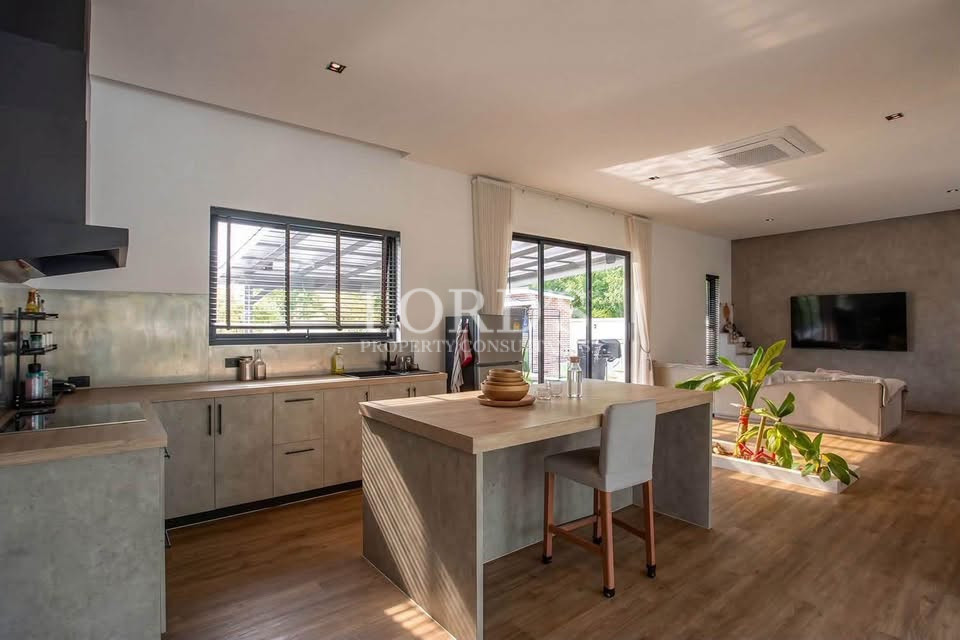 Bright kitchen and dining area with wooden island, modern cabinets, and large windows.