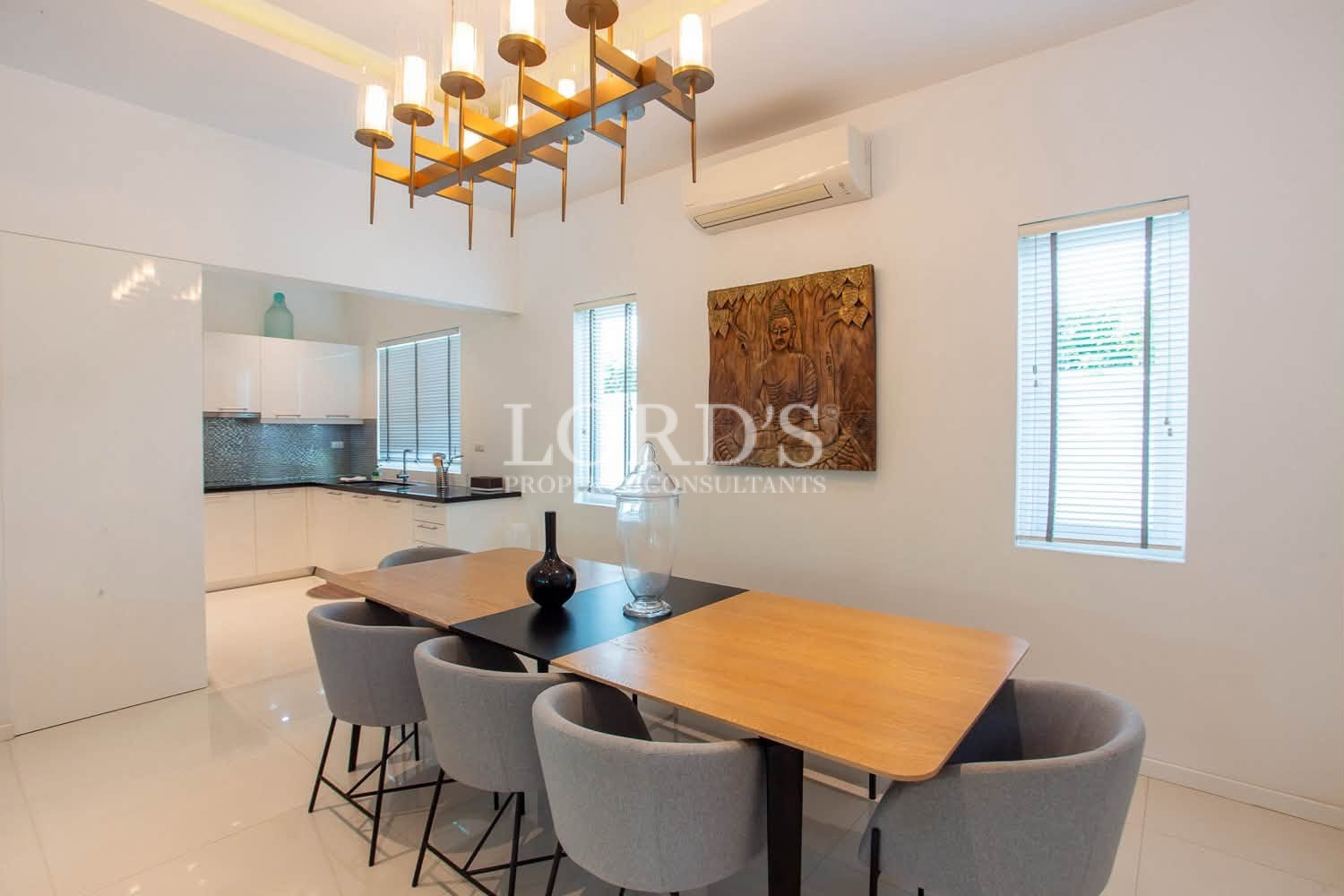 Modern dining area with wooden table, chairs, chandelier, and air conditioning