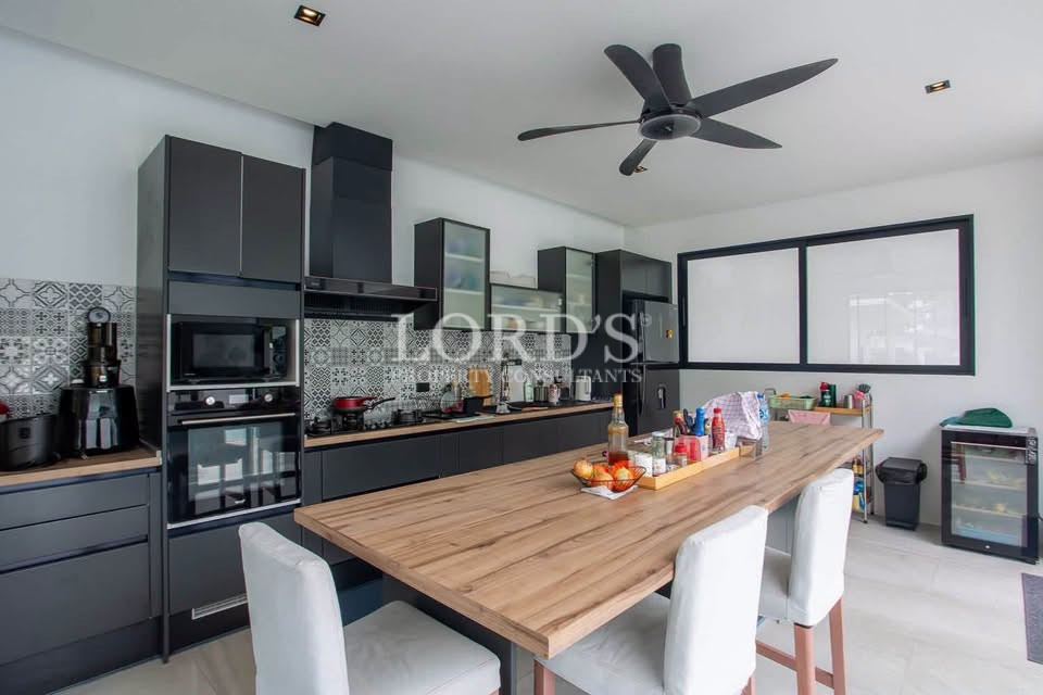 Modern open-plan kitchen with large island, black cabinets, dining area, and ceiling fan.