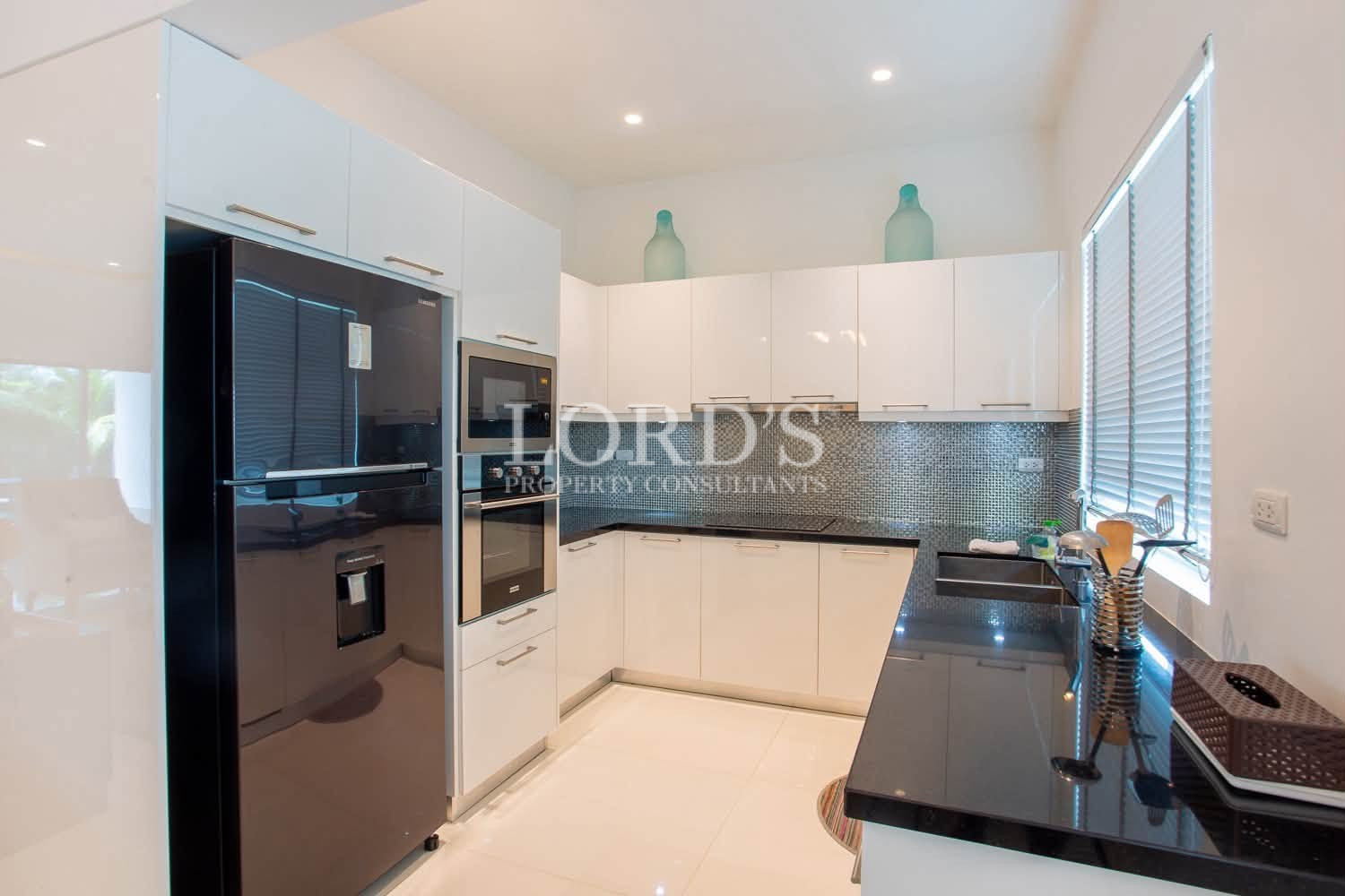 Modern white kitchen with built-in oven, cabinets, sink, and appliances