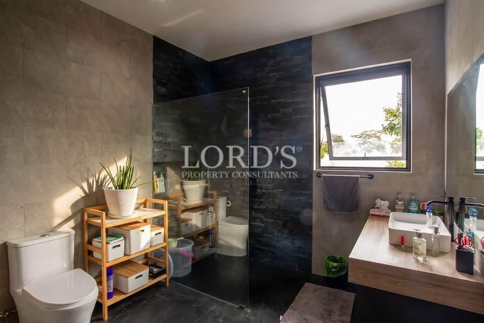Modern bathroom with dark stone tiles, wooden vanity, bathtub, and large window.