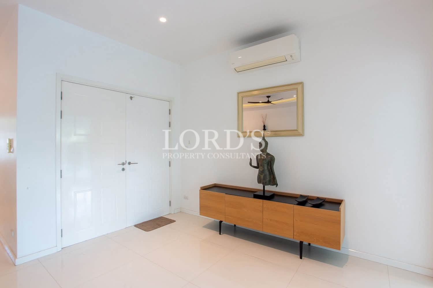 Bright modern entryway with white double doors, wooden console, mirror, and air conditioning