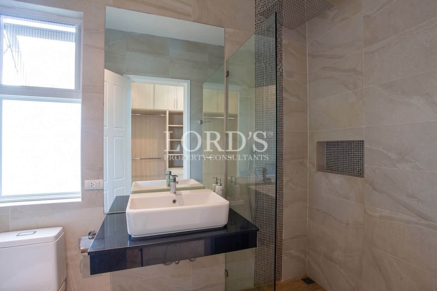 Modern bathroom with glass shower, white sink, and tiled walls