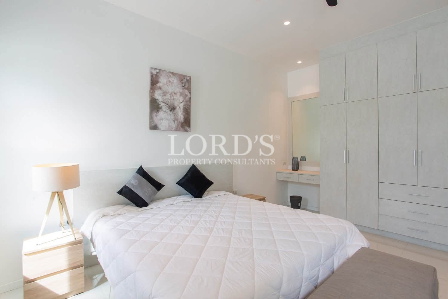 Bright bedroom with double bed, white bedding, pillows, and modern furnishings