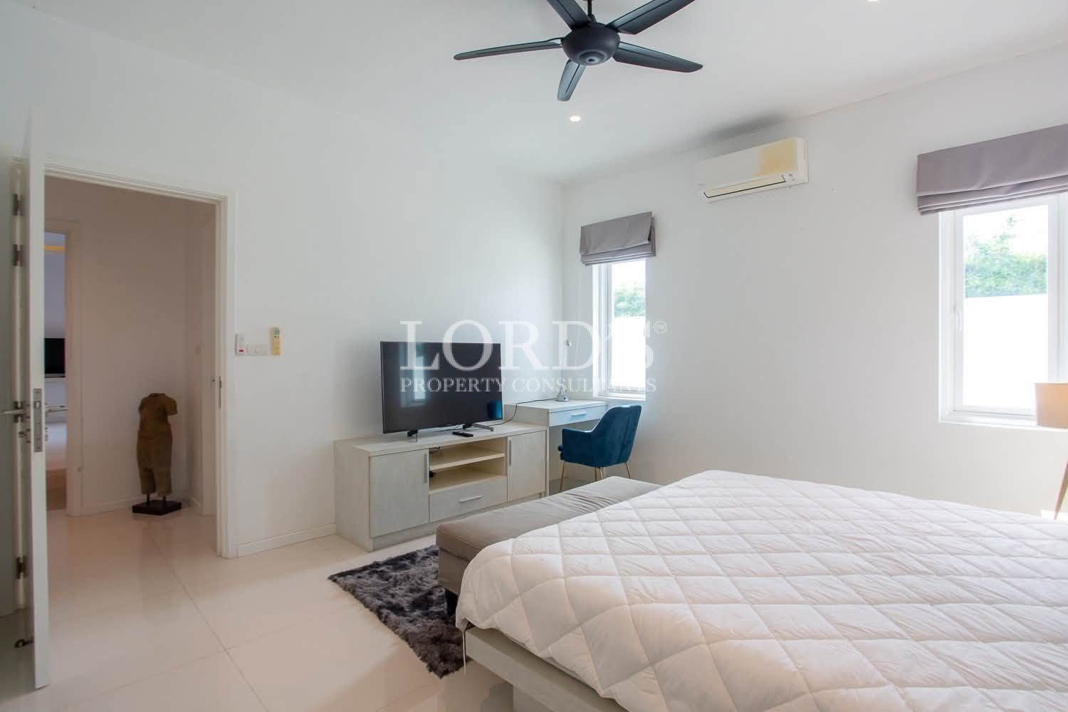 Spacious bedroom with double bed, white bedding, TV, and ceiling fan