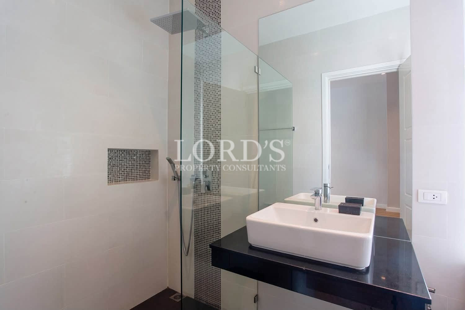 Modern bathroom with glass shower enclosure, wall tiles, and white sink