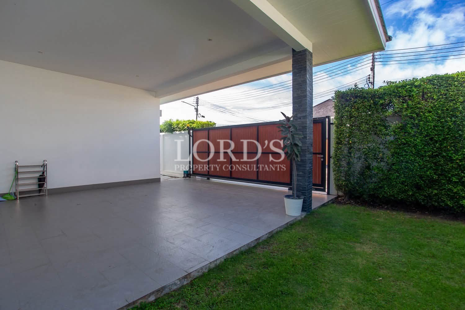 Covered outdoor carport beside a residential property with gated entrance